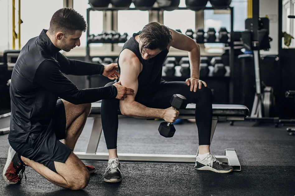 Personal trainer guiding client with dumbbell exercise in gym session