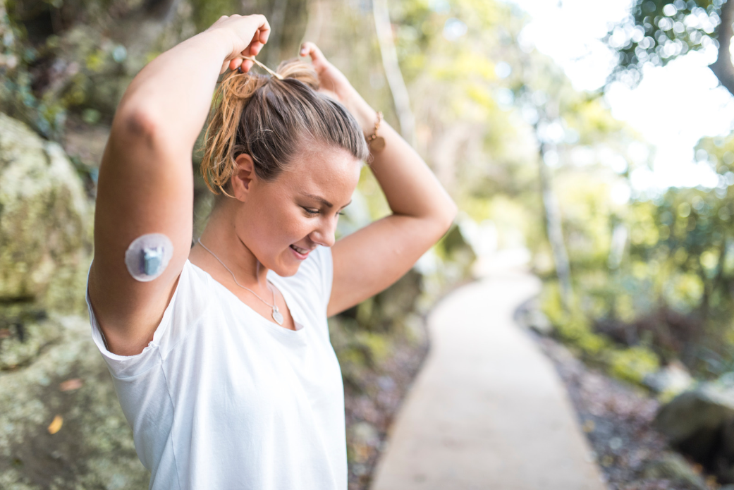 Woman walking outdoors with a glucose monitor for diabetes management