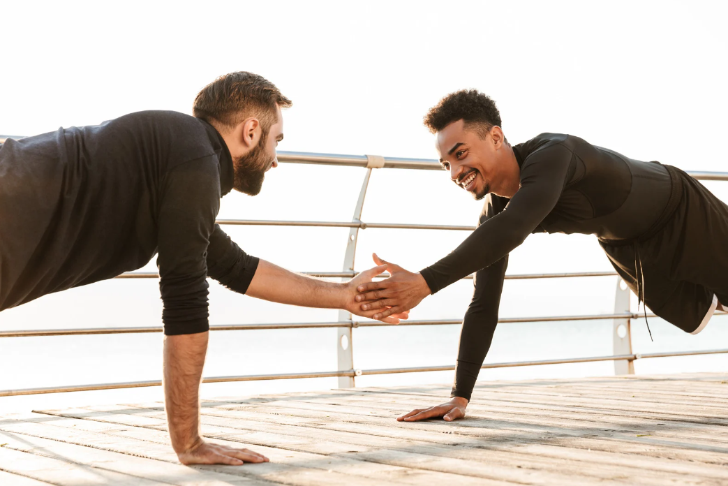 Two people holding a plank and high-fiving during partner fitness training
