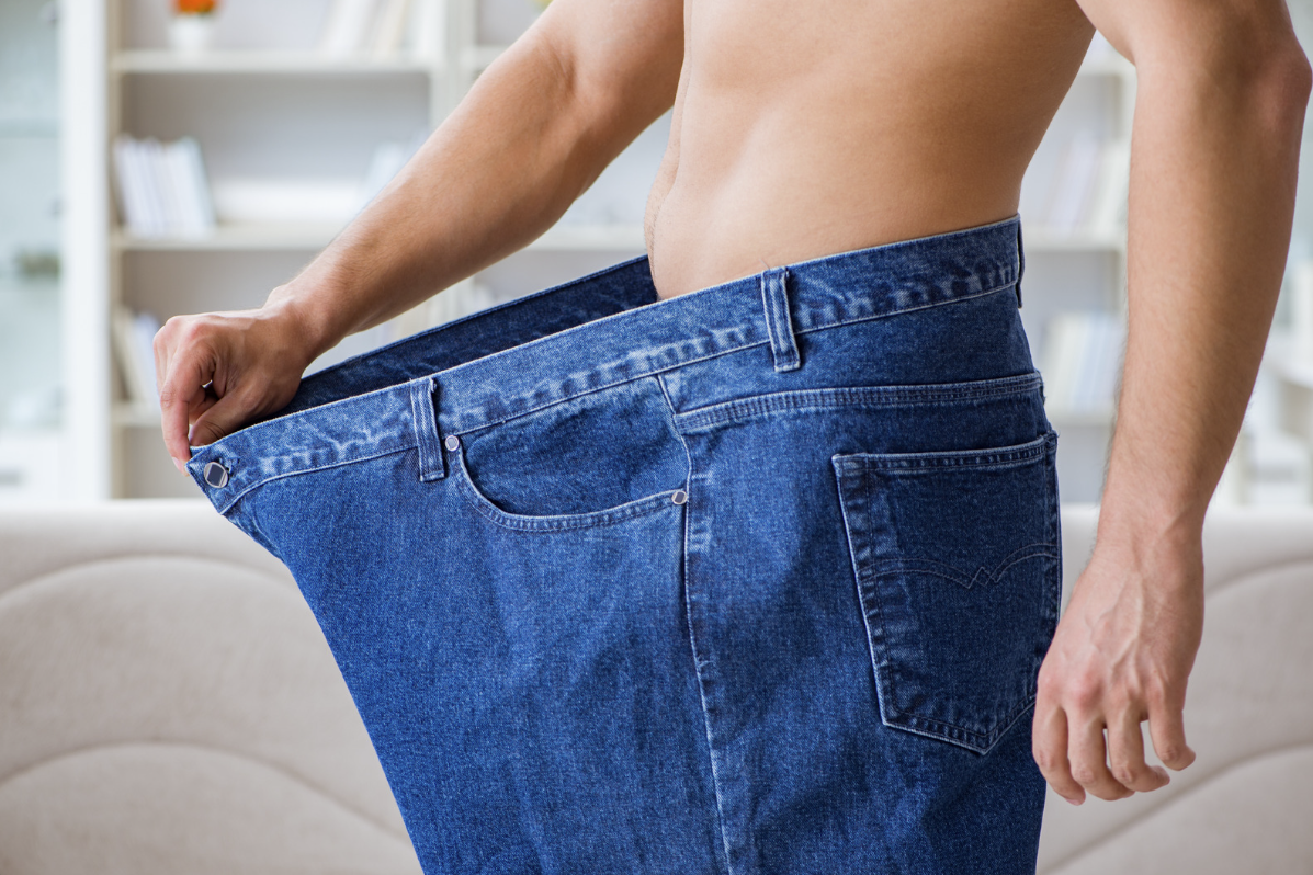 Person showing loose jeans after weight loss progress
