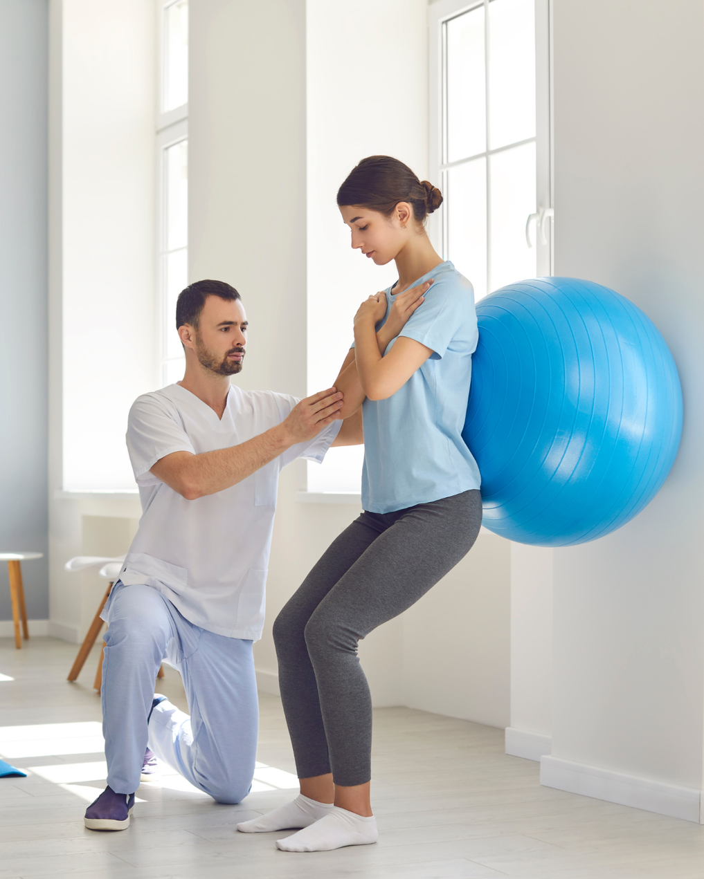 Trainer coaching a wall-squat with a stability ball to teach safe lower-body mechanics.