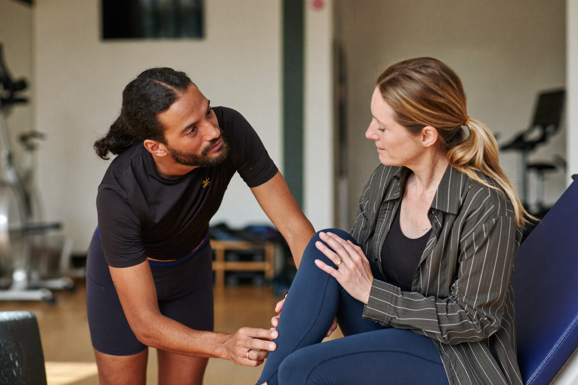 A coach listening as a client describes a knee symptom, a calm check-in about when to seek help.