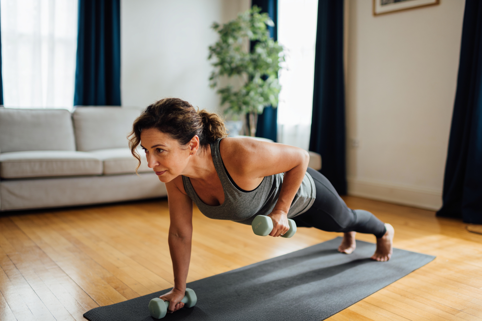 A woman doing a simple home strength workout with light dumbbells in her living room.
