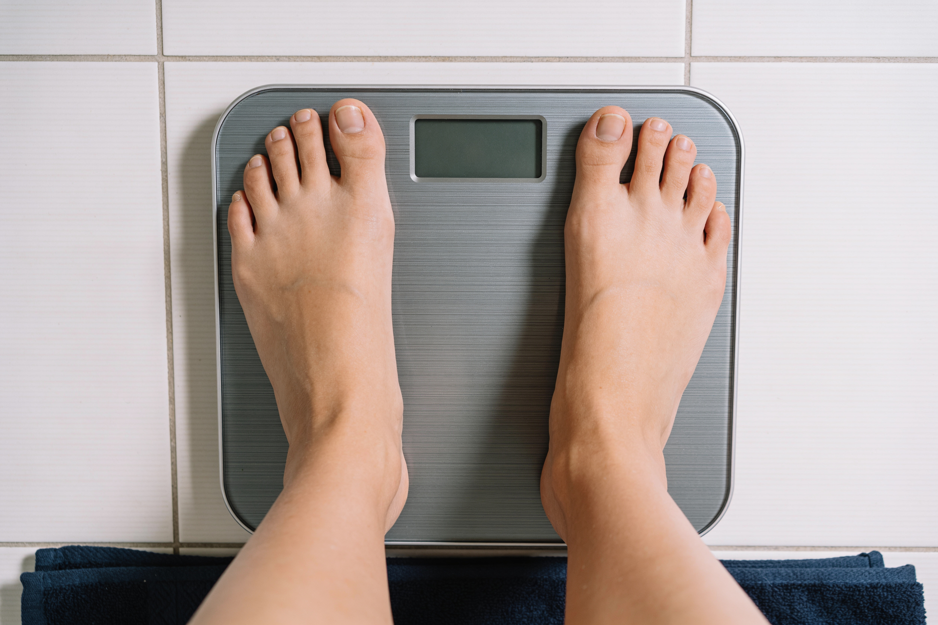 A woman’s feet standing calmly on a bathroom scale, viewed from above.