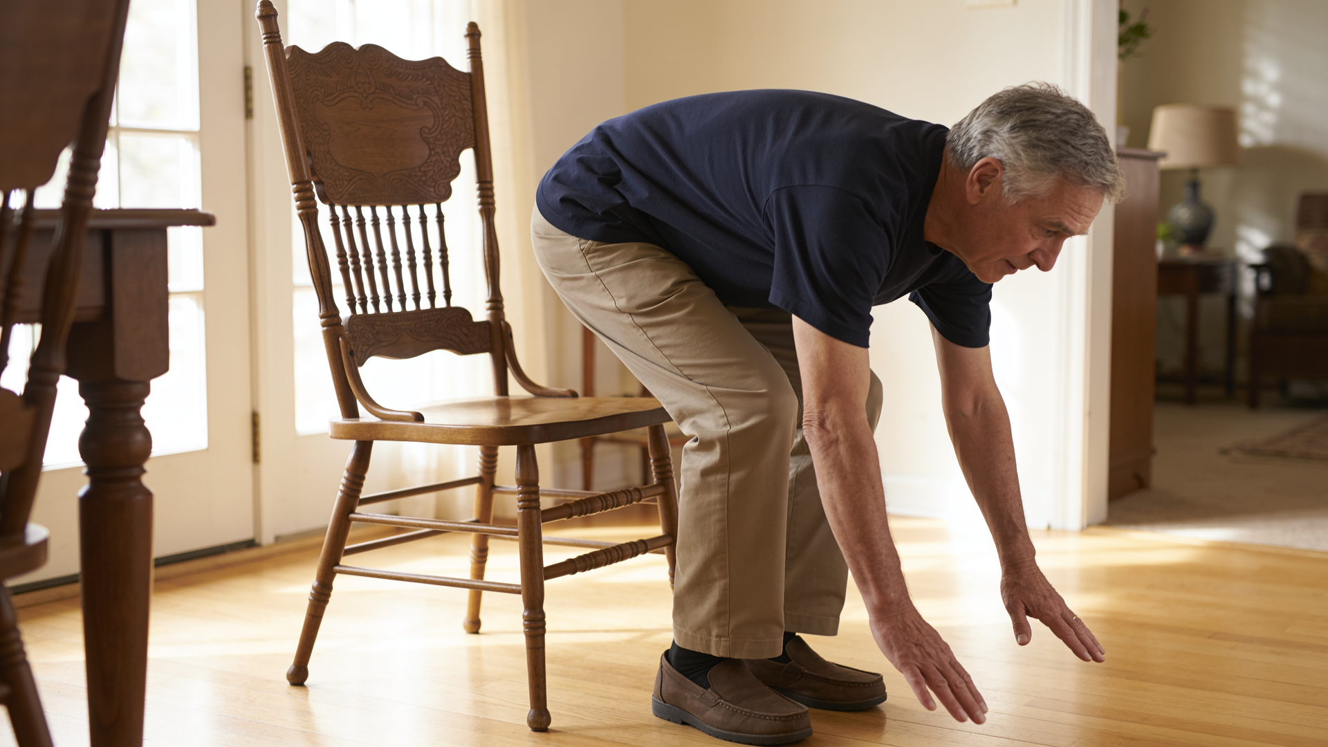 A man in his sixties rises from a chair without using his hands in a sit-to-stand test.