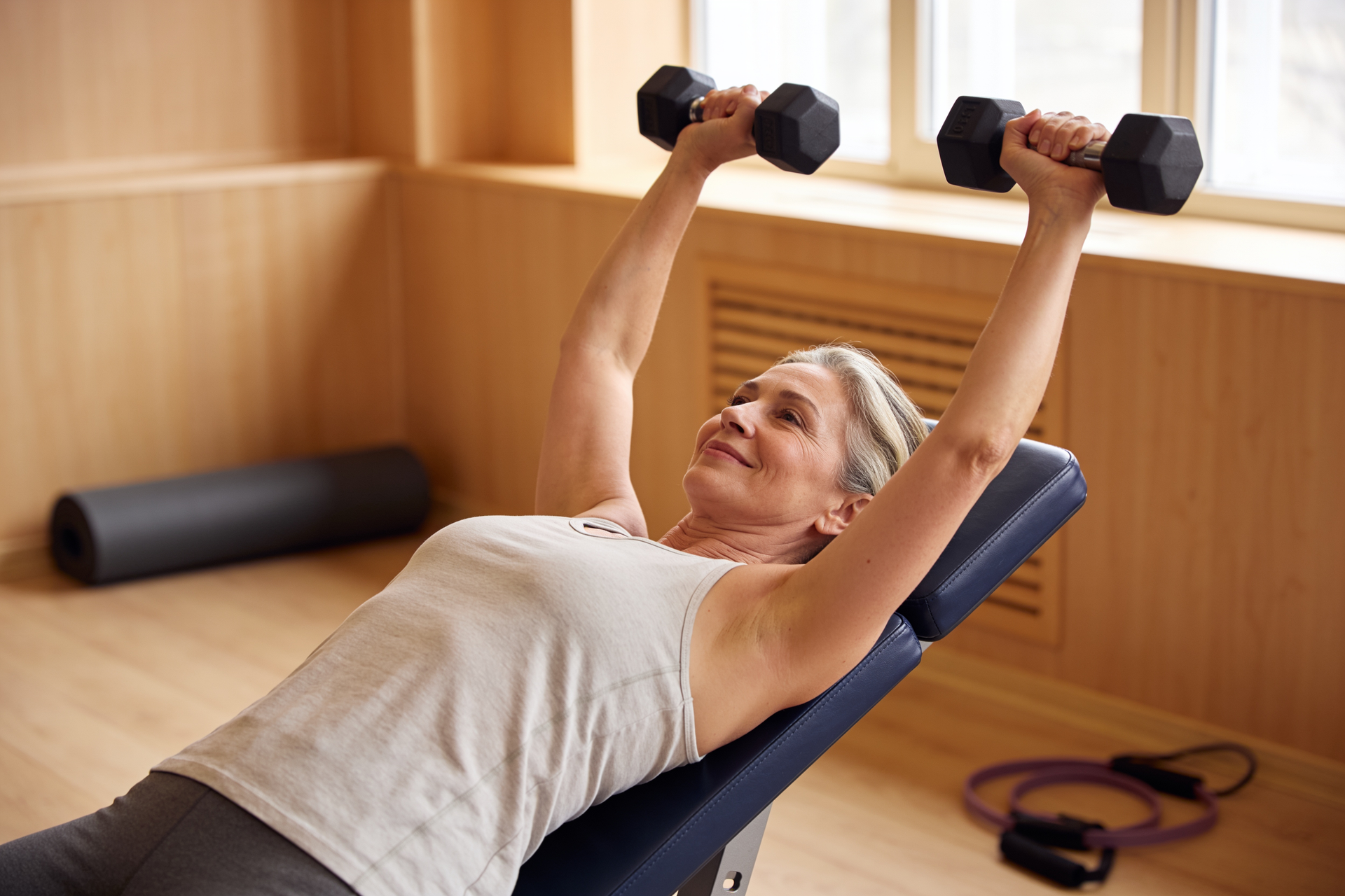 A woman performs a controlled dumbbell row with steady, consistent form.