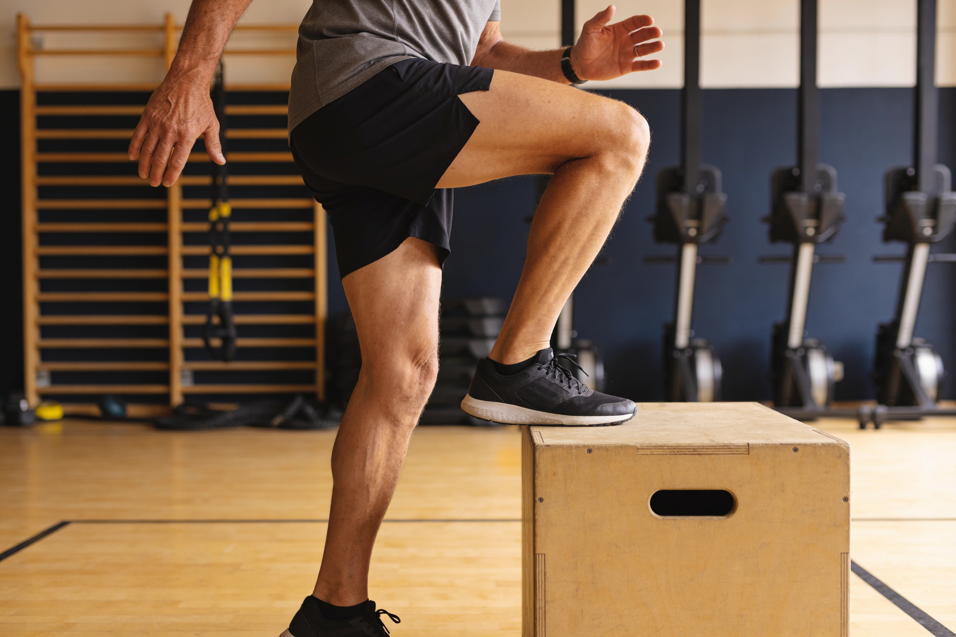 Adult doing controlled step-ups in a studio, training the legs for trail climbs and descents.