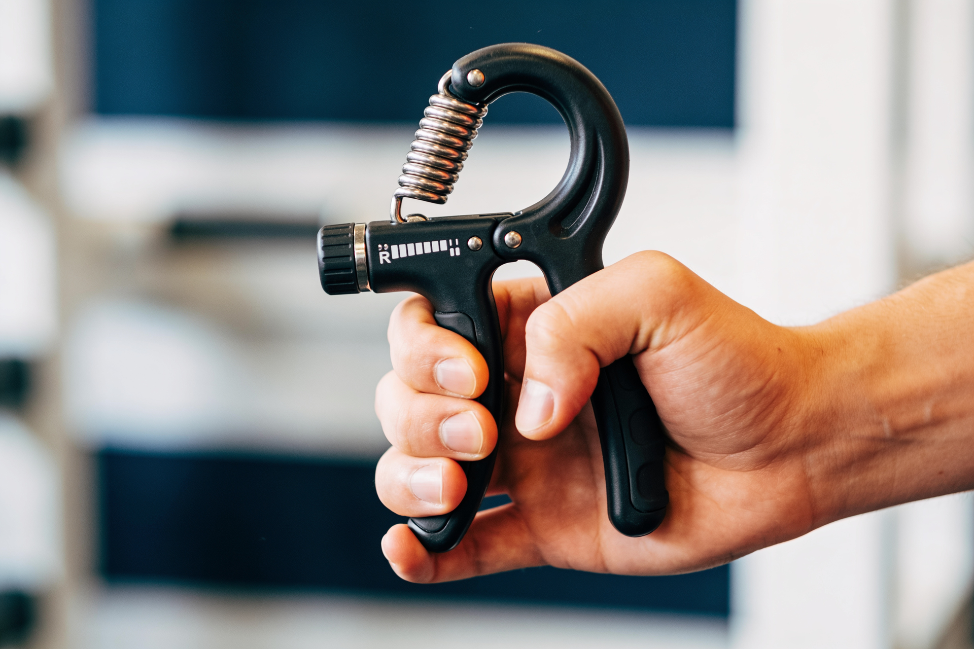 Close-up of a hand squeezing an adjustable spring hand gripper with a correct, secure hold.
