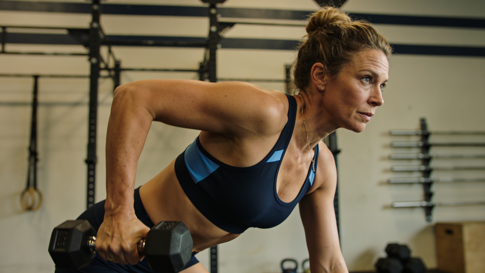 A woman in her 40s strength training with focus in a studio, strong and capable.