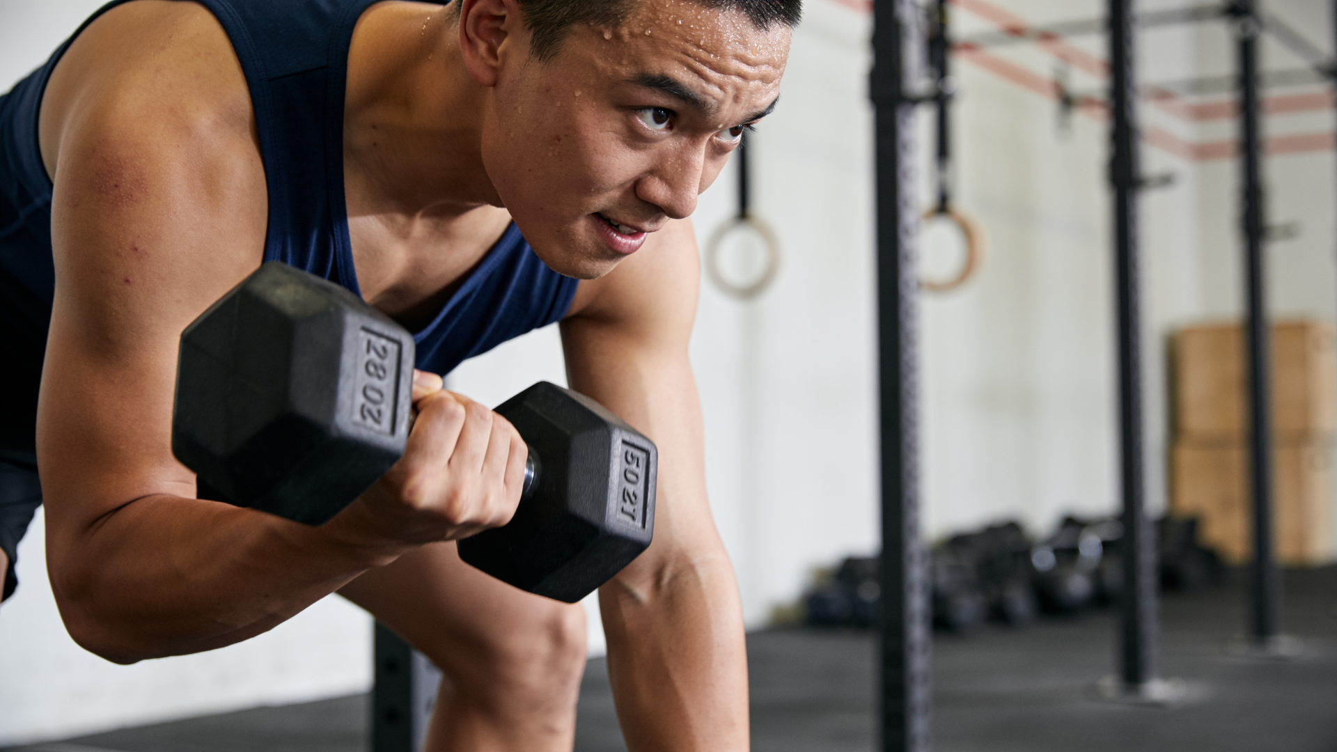 An adult mid-set of hard dumbbell work, training with focus.