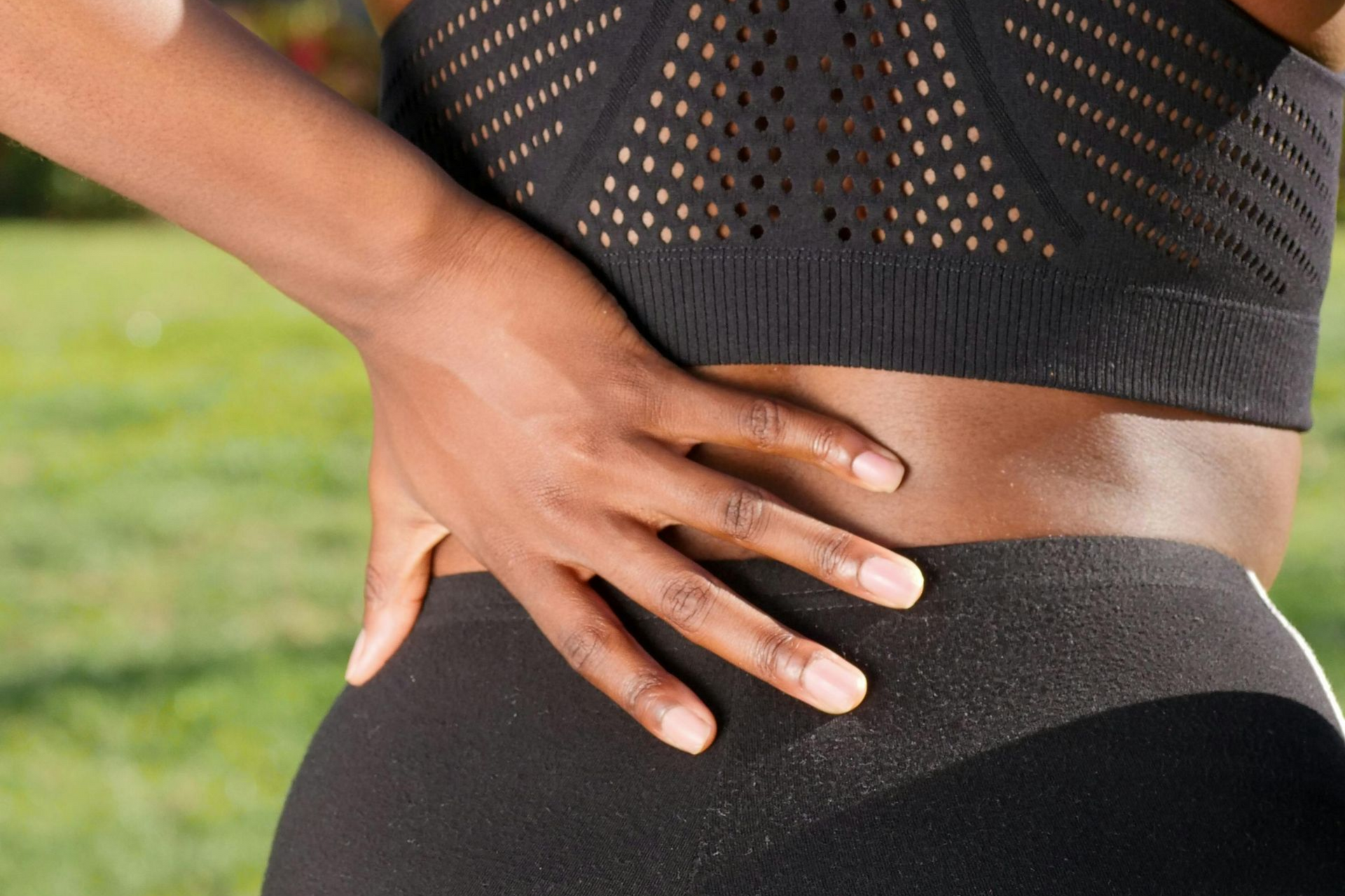 A lady is grabbing her lower left back with her left hand, indicating sciatic pain