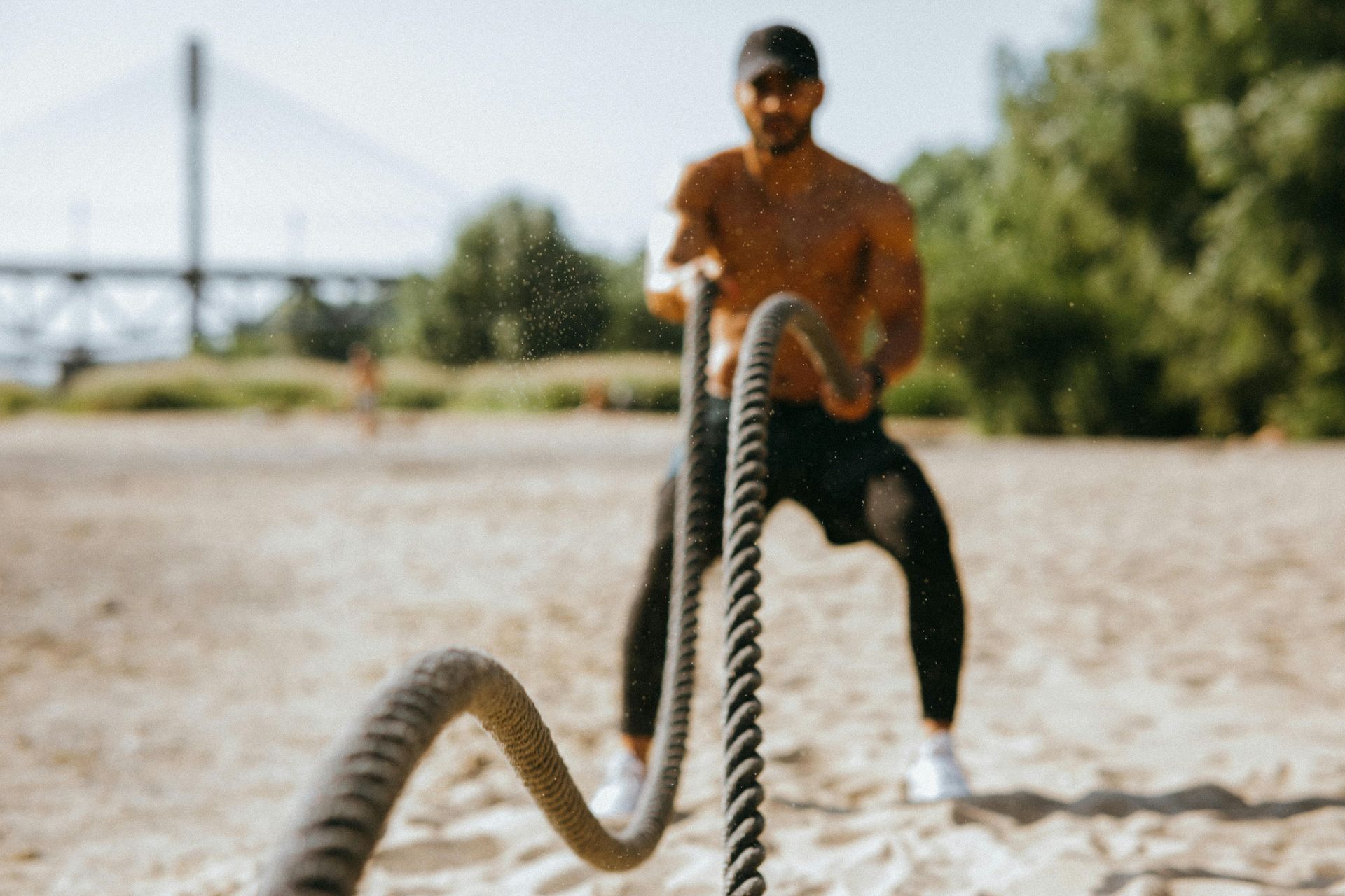 Person doing battle rope training outdoors during a summer strength workout.