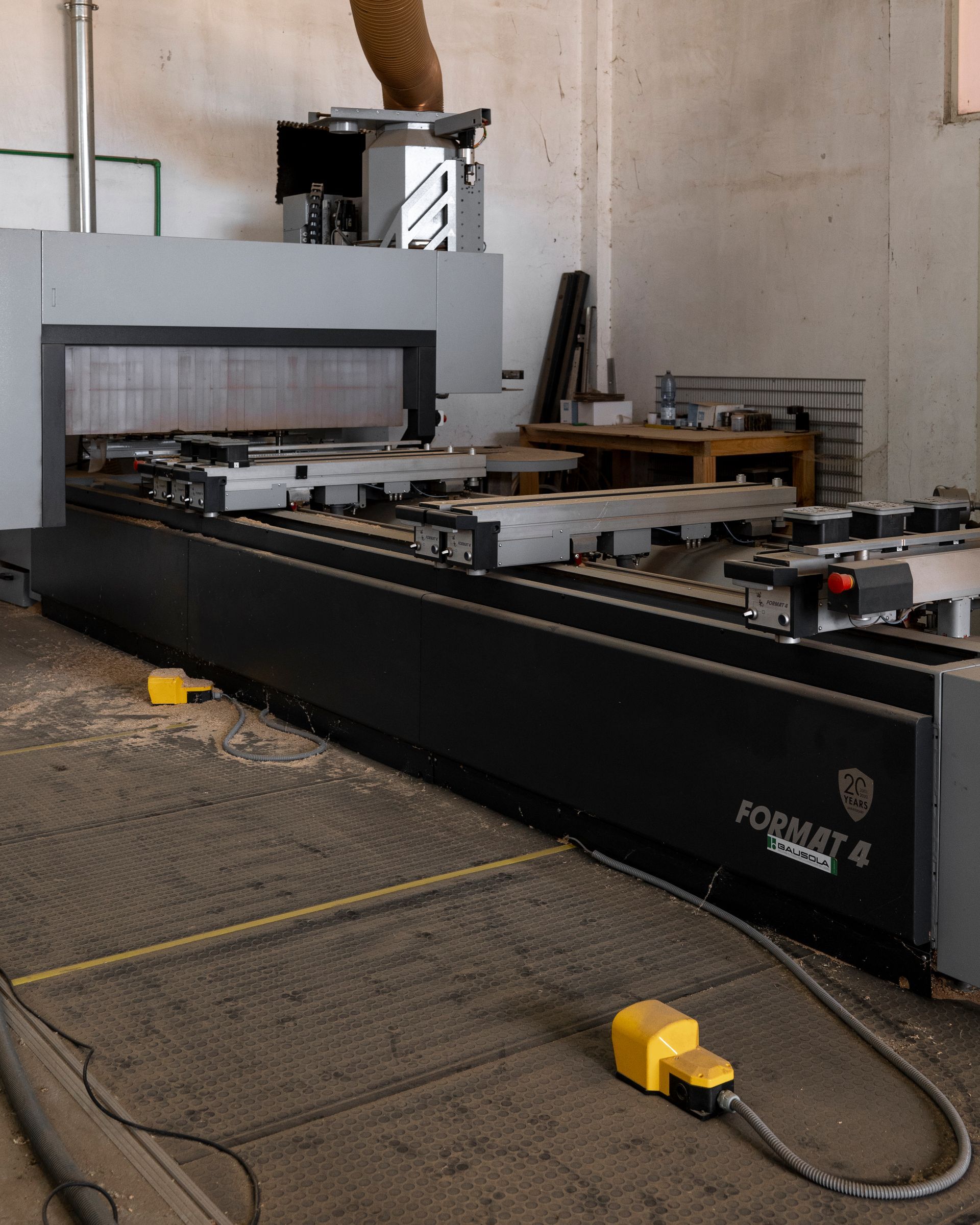 Grande macchina CNC industriale in un'officina con componenti metallici neri e grigi e comandi a pavimento gialli.