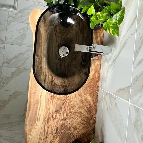 top lavandino in legno è appoggiato su un tavolo in legno in un bagno.