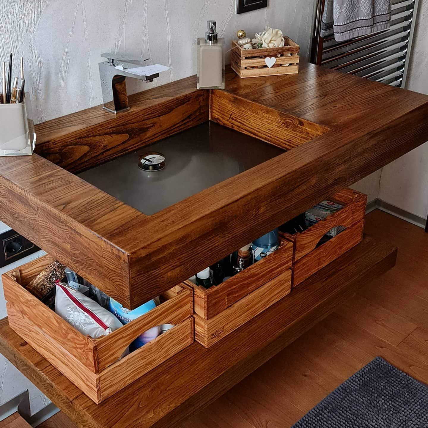 Mobile bagno con struttura in legno, lavabo integrato, cestini portaoggetti e pavimento in legno in un ambiente moderno.