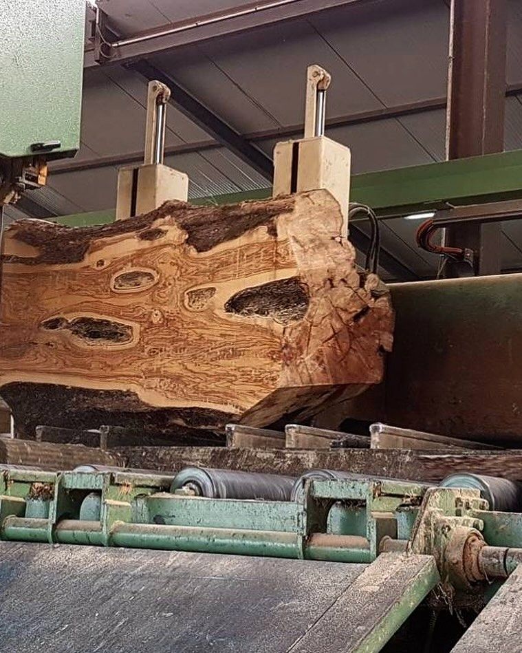 A large piece of wood is being cut by a machine.