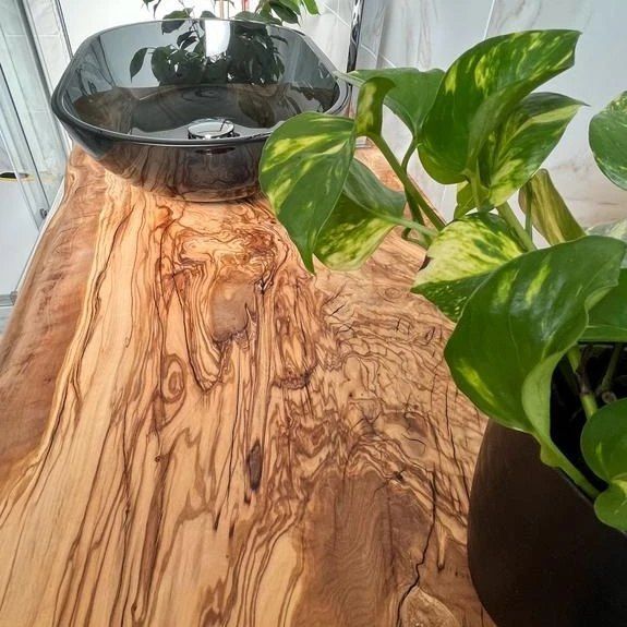 Una pianta in vaso è appoggiata su un tavolo di legno accanto a un lavandino.