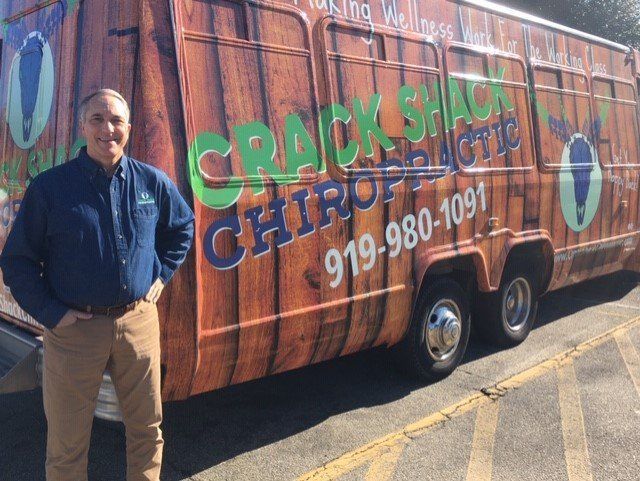 A man is standing in front of a chiropractic trailer.