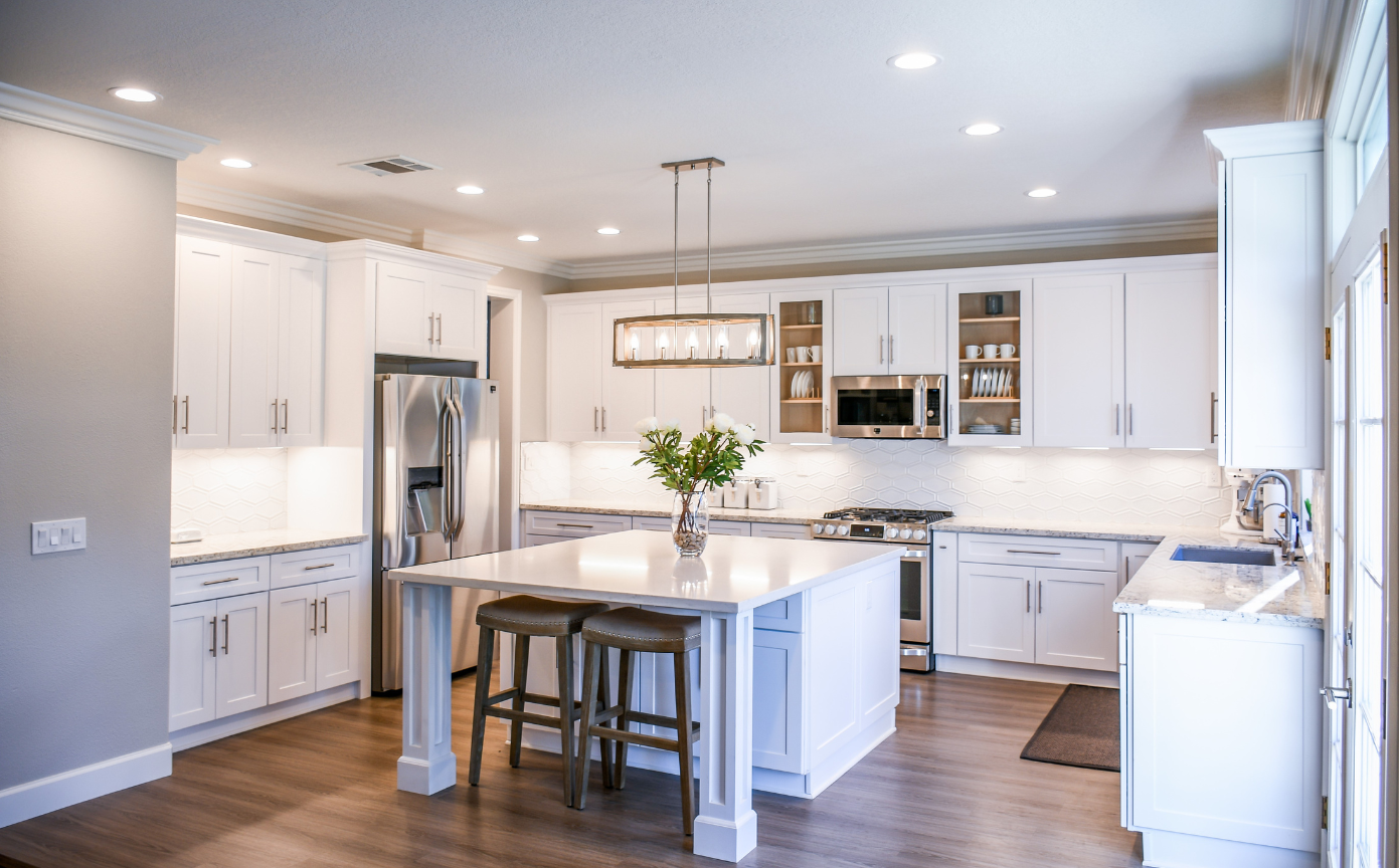 A kitchen with white cabinets , granite counter tops , stainless steel appliances and a large island.
