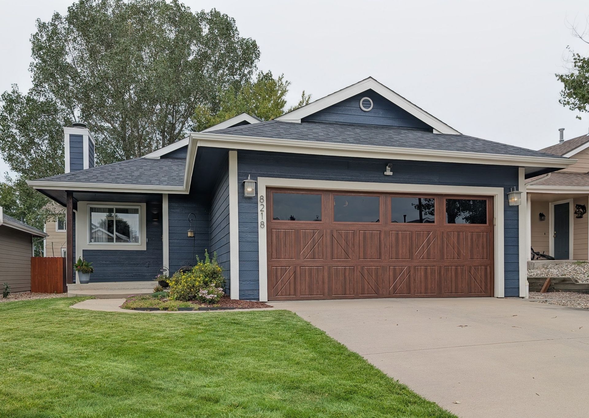 Blue house with brown garage door and green lawn on a suburban street