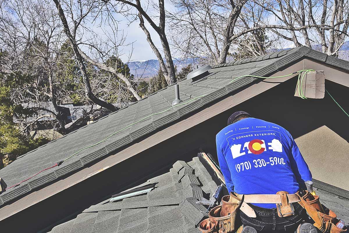Person wearing a blue Colorado helmet near a house roof with trees and mountains in the background