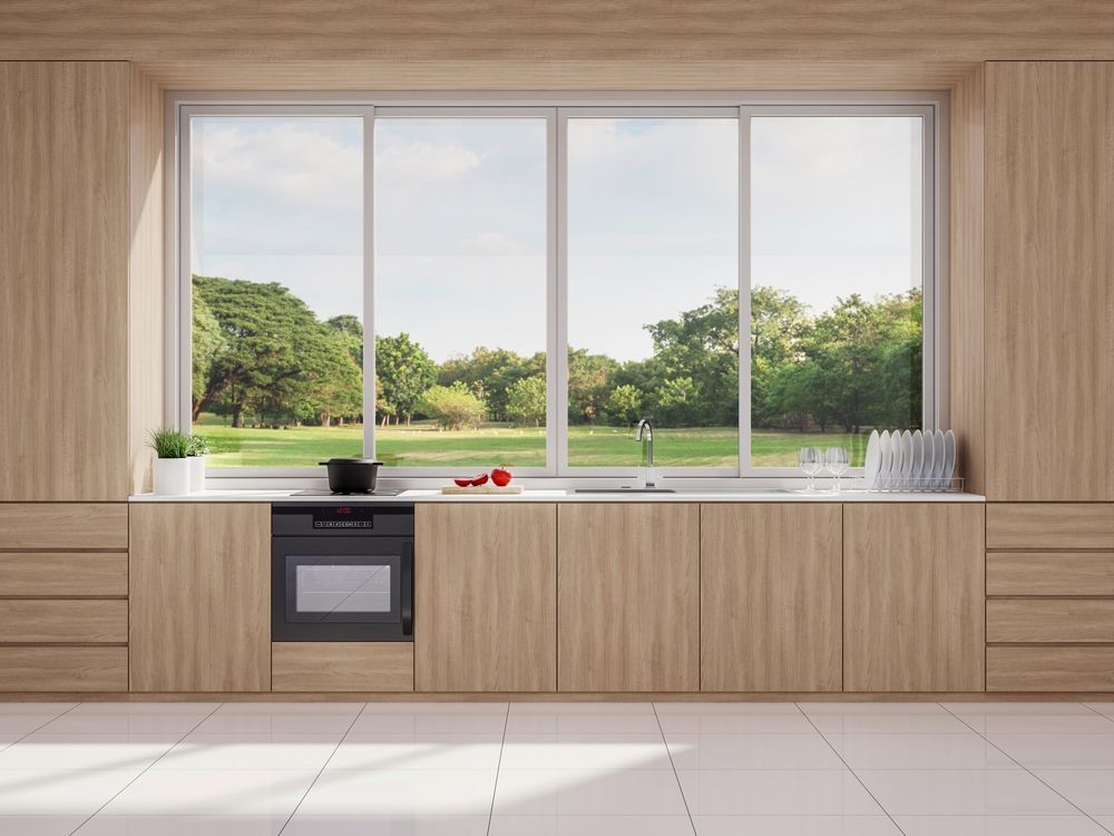 Modern Kitchen With Light Wood Cabinets, and Large Window Overlooking a Green Park — K & J Glass in South West Rocks, NSW