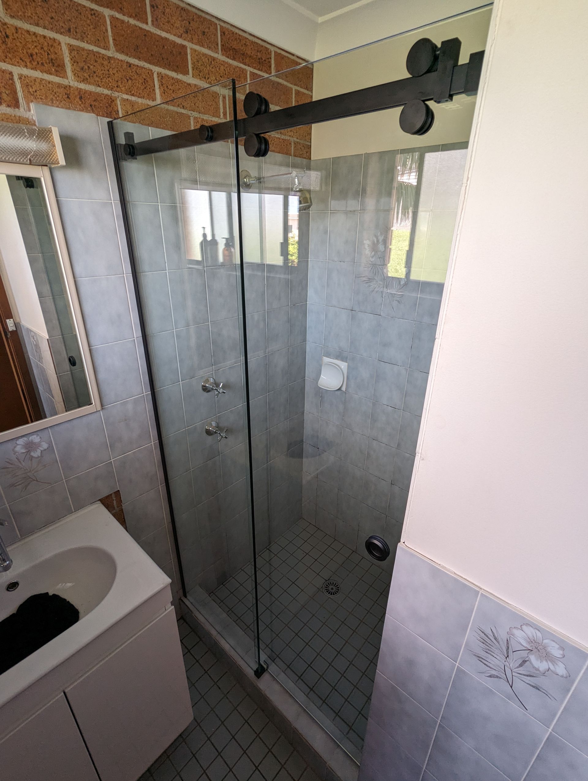 Bathroom with glass sliding shower door and black hardware; white vanity — K & J Glass in Bowraville, NSW
