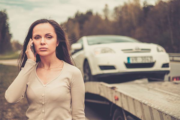 woman getting a tow, on the phone looking sad