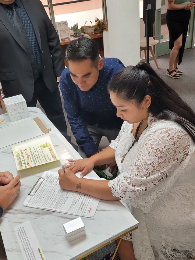 Bride signing a Marriage License as Groom Looks on