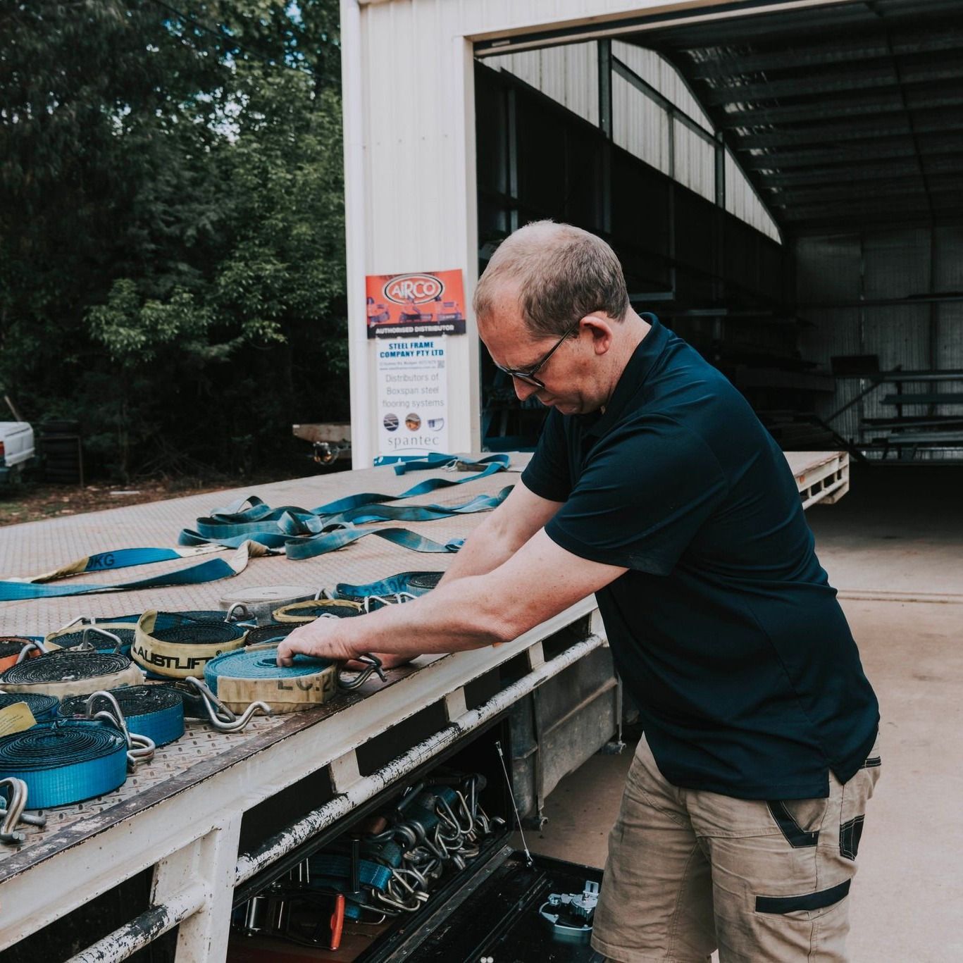 A Man in a Blue Shirt is Working on a Truck — Steel Frame Company In Mudgee, NSW
