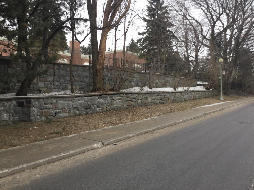 Un mur de pierre le long d'une route avec des arbres en arrière-plan