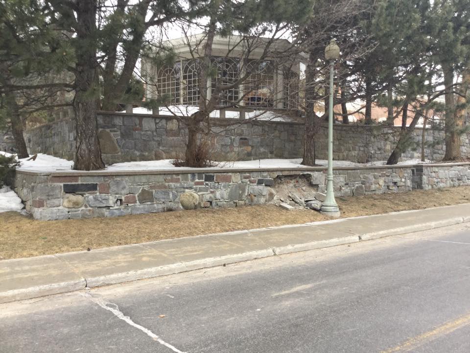 Un mur de pierre au bord d'une route avec un bâtiment en arrière-plan