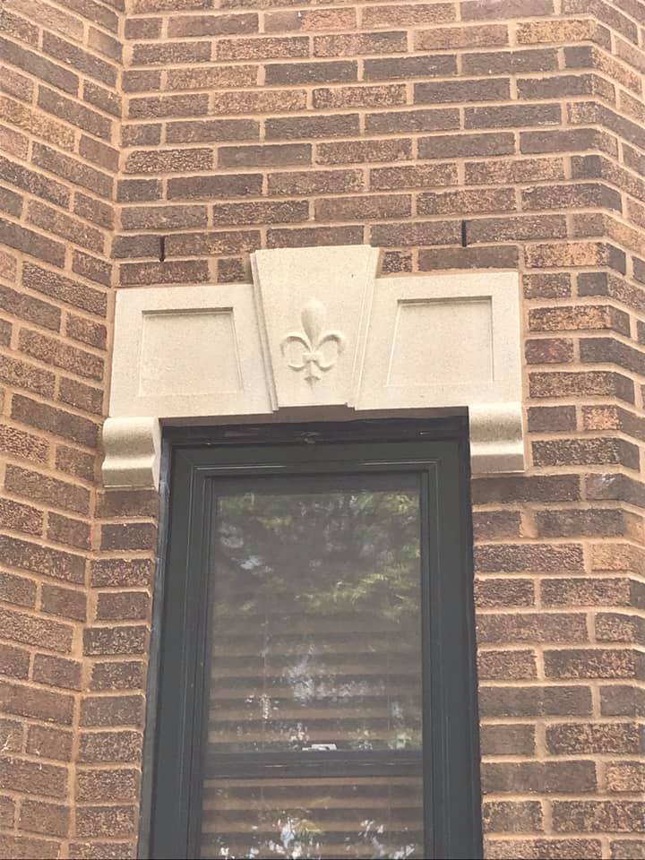 Un bâtiment en brique avec une fenêtre et une fleur de lys dessus