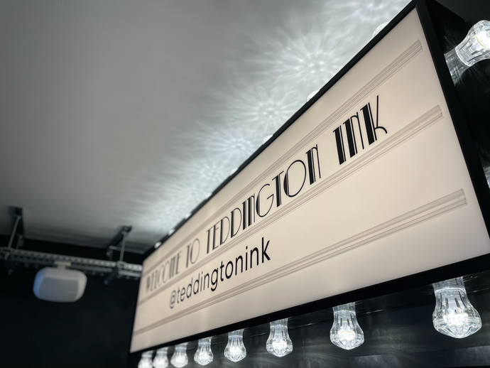 Large indoor event banner reading “TRUE ATTORNEY BIK” with “bikagroupink” below, lit by hanging bulbs