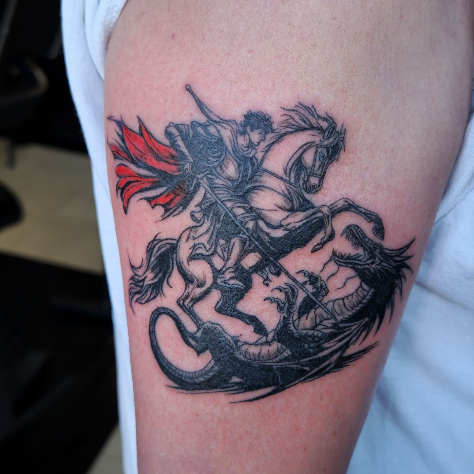 Black-and-red dragon tattoo on a person’s upper arm