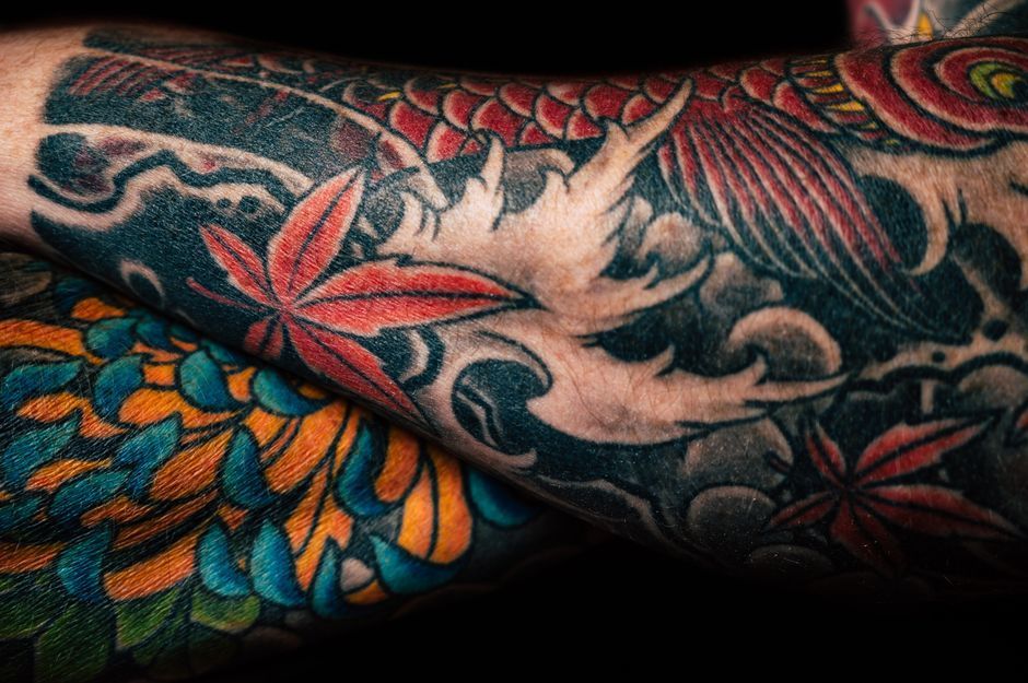 Close-up of colorful floral and dragon tattoo on a forearm