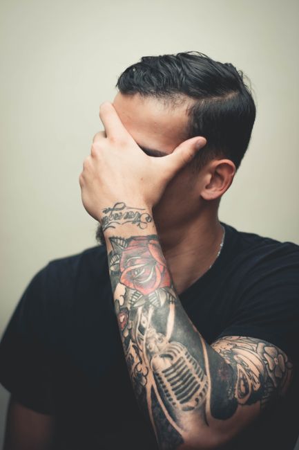 Tattooist applying a cover-up tattoo design over an existing faded tattoo