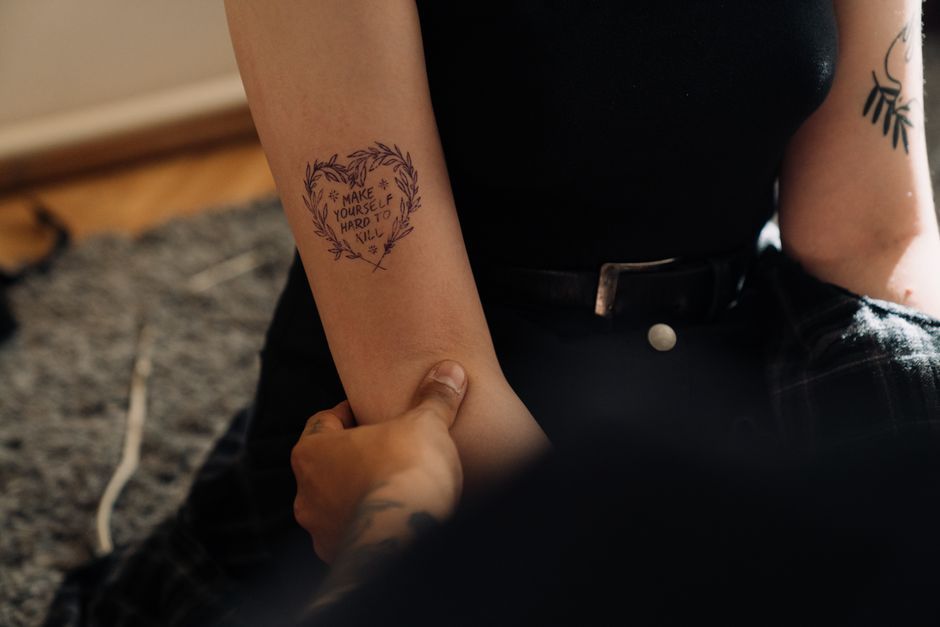 Tattooist marking a tattoo placement on a client's shoulder during a consultation