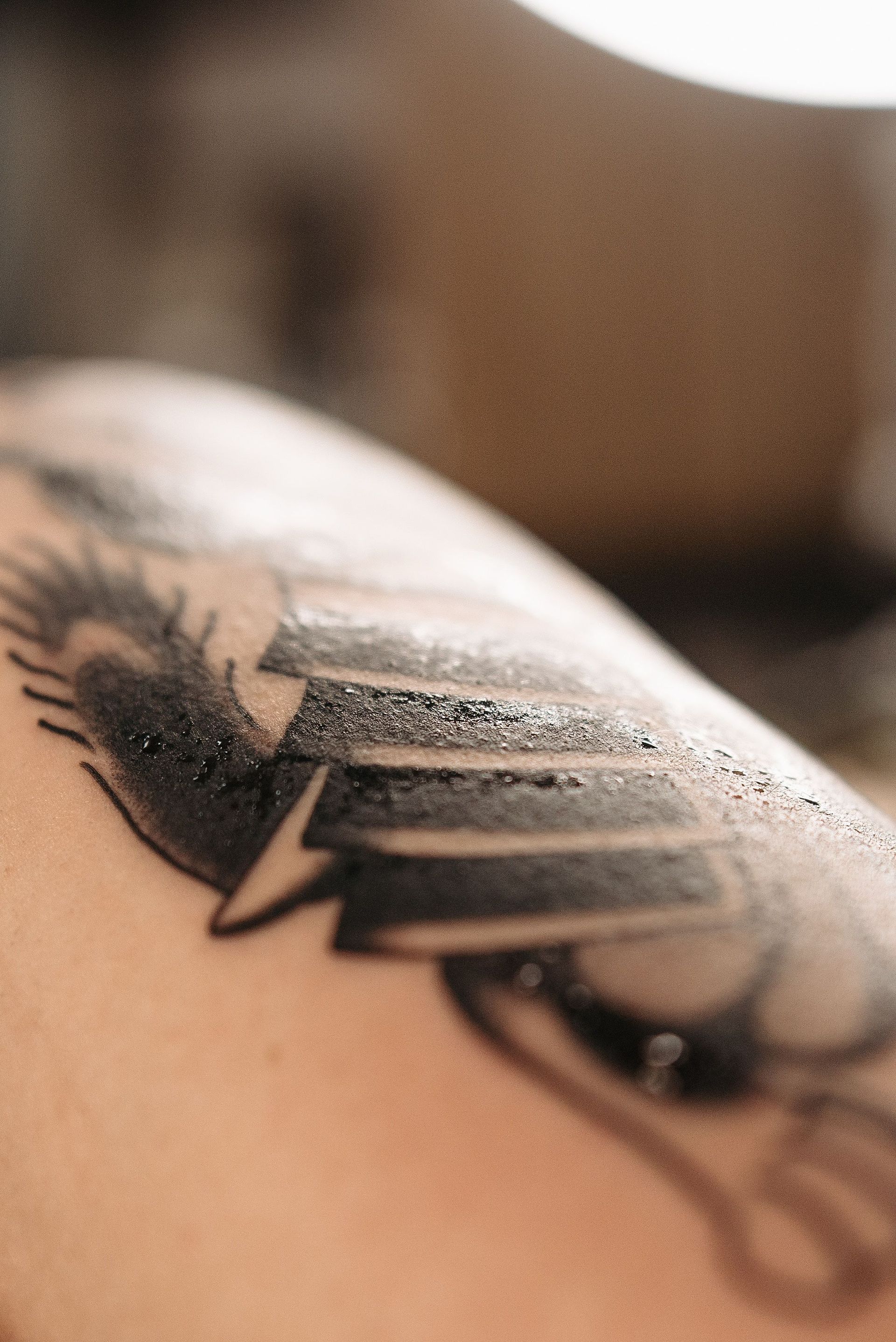 Close-up of a black tattoo on skin, with a feather-like design and bold stripes
