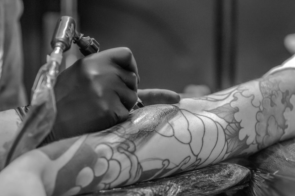Tattooist performing a touch-up session on a healed tattoo