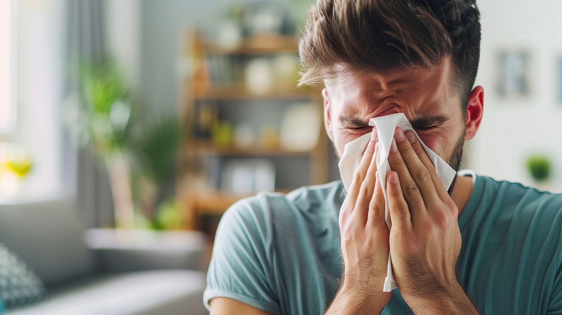 Person blowing their nose with a tissue in a bright living room