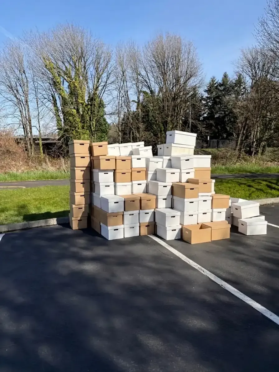 Stack of file boxes staged in a parking lot for an on-site paper shredding pickup