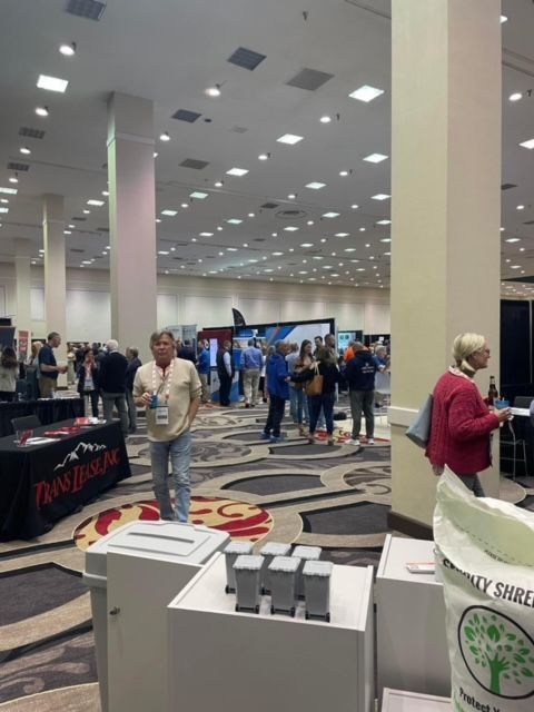 A group of people are gathered in a large room with a table that says dash foods on it