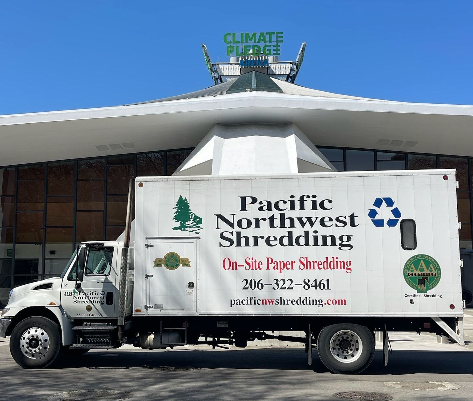 A pacific northwest shredding truck is parked in front of a building