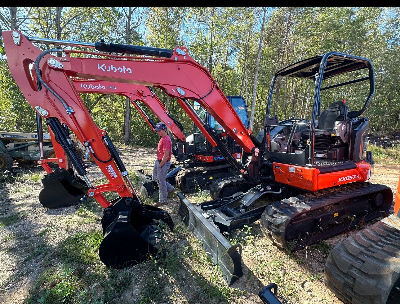 Red Kubota excavator with a grapple attachment, outdoors.
