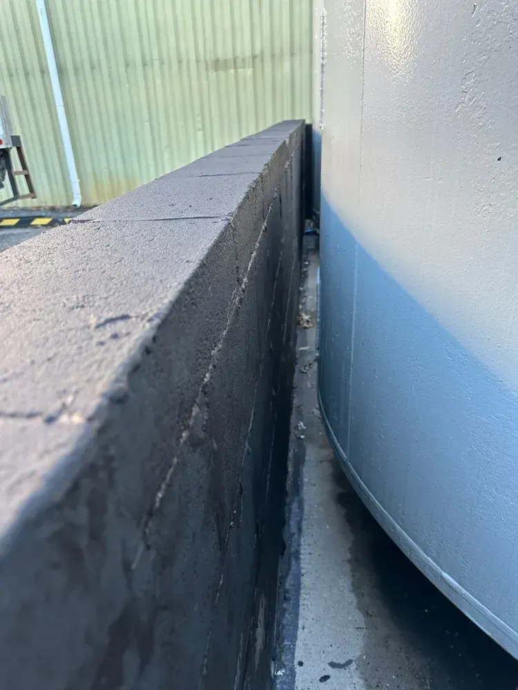 A gray tank is sitting next to a black wall.