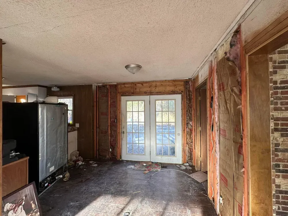 An empty room with a refrigerator and sliding glass doors.
