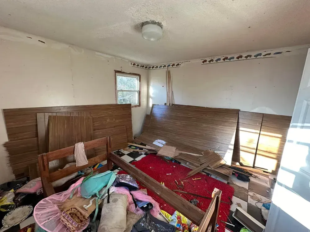 A messy room with a bed and a window.