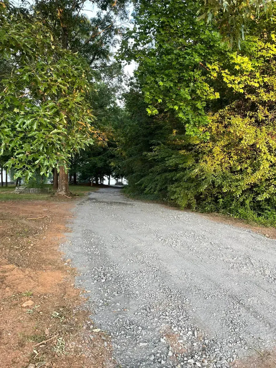 A gravel driveway leading to a house surrounded by trees.