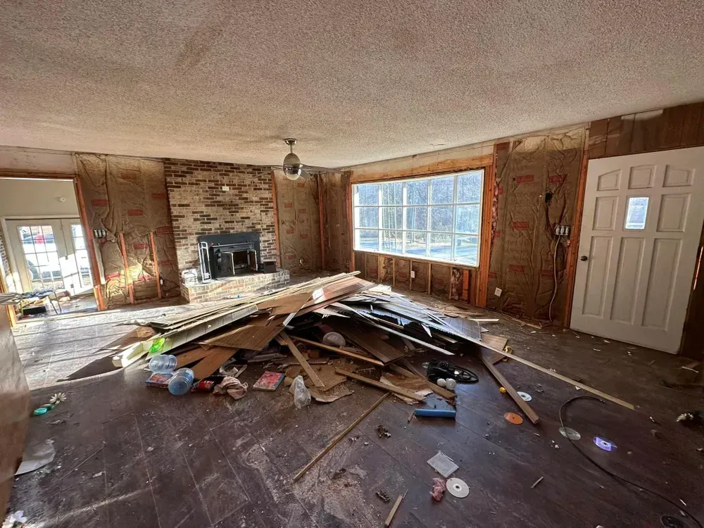 A living room with a lot of junk on the floor and a fireplace.